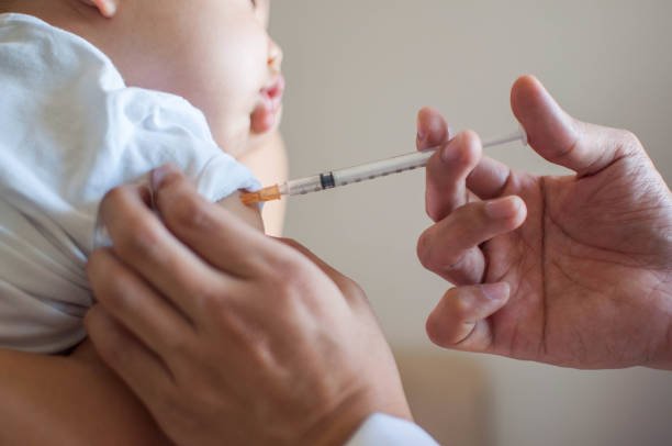 A pediatrician gently administering a vaccine to a calm baby during an immunization visit