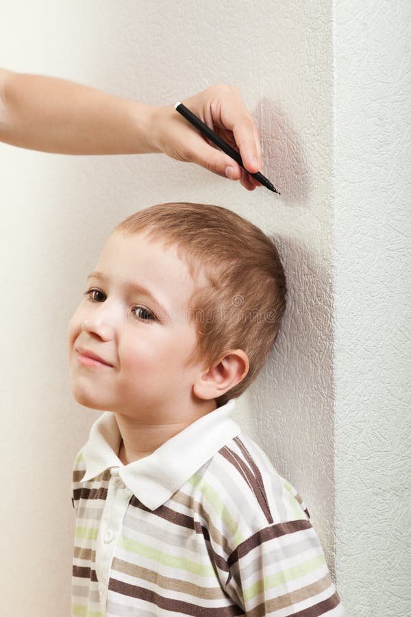 Hands gently measuring a child's height against a wall