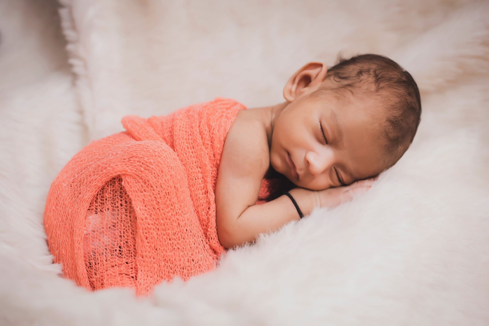 A newborn baby sleeping peacefully in a soft white swaddle