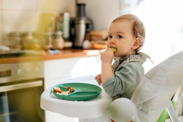 A happy baby girl eating her meal at a high chair